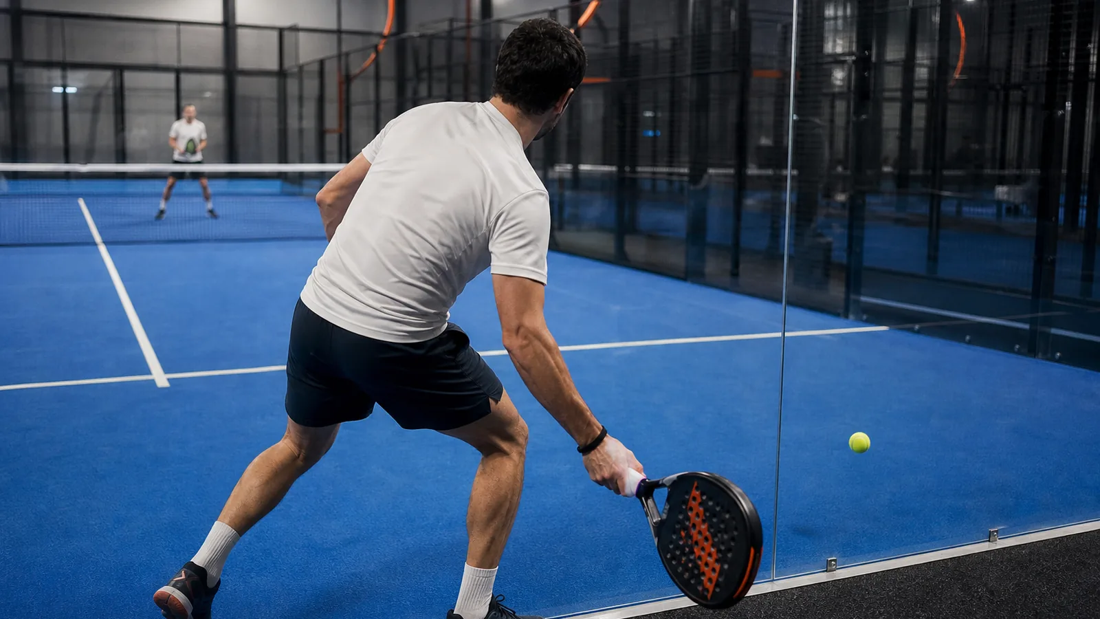 Padelspeler bereidt een return voor nadat de bal van de achterwand terugkomt